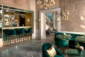 a bar with green chairs and a man in the mirror at Hotel Gabrielli Venezia - Starhotels Collezione in Venice
