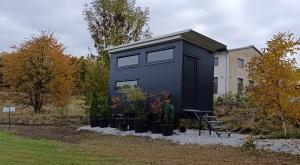 a black tiny house in front of a building at Boží maringotka in Humpolec