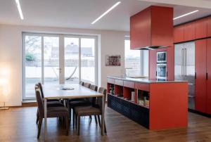 RovaniemiApartment with 3BDR - private Jacuzzi & Sauna的厨房配有红色橱柜和桌椅