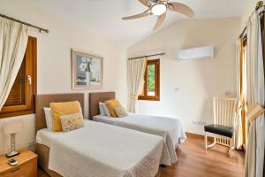 a bedroom with two beds and a ceiling fan at Beautiful Villa Pera with private pool and lovely gardens, Aphrodite Hills in Kouklia +29 photos