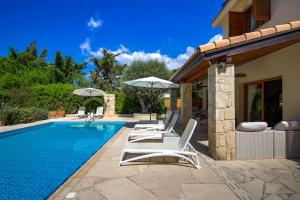 a swimming pool with white lounge chairs and a house at Beautiful Villa Pera with private pool and lovely gardens, Aphrodite Hills in Kouklia