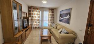 a living room with a couch and a television at Arinaga Beach & Pool Apartment in Arinaga