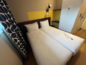 a bedroom with two beds with white sheets at Unisotel Lyon Bron Eurexpo in Bron