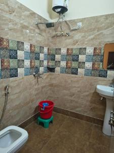 a bathroom with a toilet and a sink and a bucket at Bhagirathi Residency in Rishīkesh