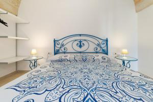 佩斯科勒海滨Villa Lantana by SALENTOLTREMARE的一张蓝色的白色床,位于带两张桌子的房间