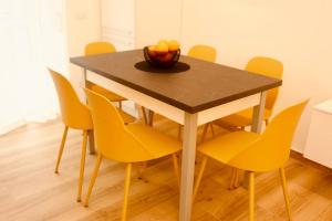 a dining room table with yellow chairs and a bowl of fruit at Le Rotte di Antonella in Lido di Ostia