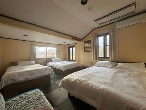 Un dormitorio con dos camas y dos ventanas. en Yukiguni Base Hakuba, en Hakuba