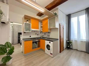 una cucina con armadi arancioni e lavatrice di Mondo House a Bologna