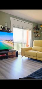 een woonkamer met een bank en een flatscreen-tv bij Casa con mucha luz natural in Bisbal del Penedès
