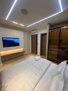 una camera da letto con un grande letto bianco e una TV a schermo piatto di Chizzly Apartment a Bamgbose