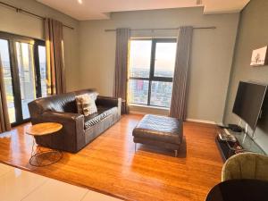 sala de estar con sofá de cuero y silla en Lofty-Space, en Gaborone