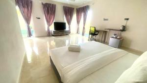 a bedroom with a large white bed and a television at Capital O 91246 Tokman Inn in Pantai Cenang