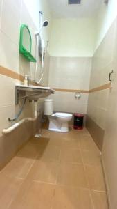 a bathroom with a toilet and a sink and a mirror at Capital O 91246 Tokman Inn in Pantai Cenang