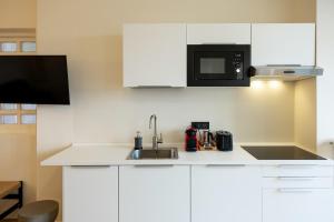 eine weiße Küche mit Spüle und Mikrowelle in der Unterkunft Domus Nova - Una finestra sui tetti in Turin + 18 Fotos