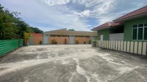 an empty parking lot in front of a building at Capital O 91246 Tokman Inn in Pantai Cenang