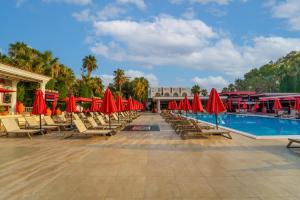una piscina con tumbonas y sombrillas rojas en Club Hotel Sera, en Antalya