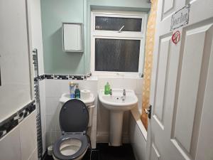 a small bathroom with a toilet and a sink at Rosag Guest House Rainham in Rainham