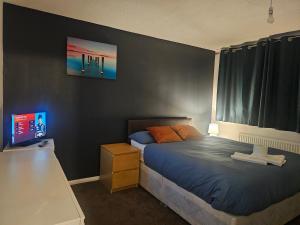 a bedroom with a bed and a desk and a television at Rosag Guest House Rainham in Rainham