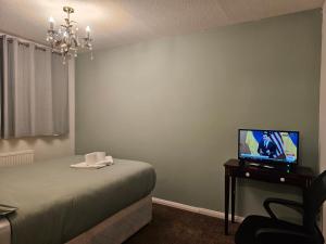 a bedroom with a bed and a tv on a table at Rosag Guest House Rainham in Rainham