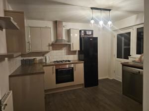 a kitchen with a black refrigerator and a stove at Rosag Guest House Rainham in Rainham