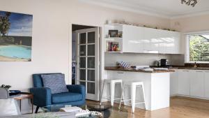 Pretty BeachNumber 96 At Pretty Beach By Holidayco的一间厨房,里面配有白色橱柜和蓝色椅子