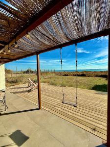 a porch with a swinging bench on a deck at La Cabane du Pêcheur, Clim et bord d'étang! in Pérols