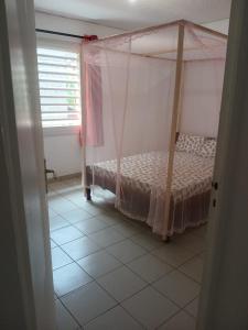 ein Schlafzimmer mit einem Himmelbett und Fliesenboden in der Unterkunft Dago-Nid Baobab Appartement in Mamoudzou