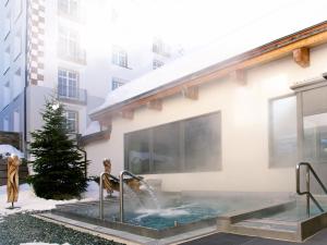 a hot tub in the courtyard of a building at Schweizerhof Ferienwohnungen Lenzerheide Haus 5 in Lenzerheide