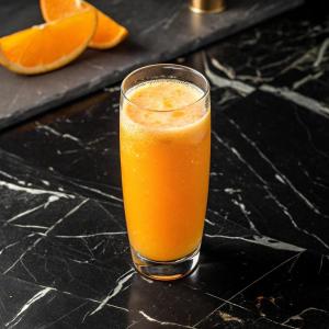 a glass of orange juice sitting on a table at El Fares Hôtel Spa & Conférences in Bordj Bou Arreridj