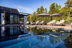 una piscina con sedie e ombrelloni accanto a una casa di Diggers Country House a Tulbagh