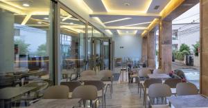 un restaurante con mesas, sillas y ventanas en Hotel Pandora Residence, en Tirana