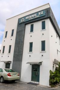 拉各斯House 32 Hotels and Suites的一栋白色建筑，前面停着一辆汽车