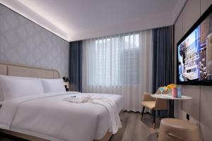 Huanman Hotel Changsha Yuelushan Yingwan Town Metro Station Branch في تشانغشا: غرفة فندق مع سرير وتلفزيون