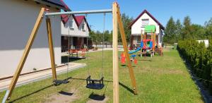 a playground with swings in a yard with houses at Nautica in Gąski