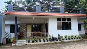 a small white house with a balcony at Manna Homestay coorg in Kushālnagar +9 photos
