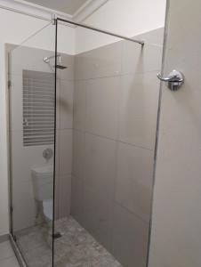 a bathroom with a glass shower with a toilet at Melkbos Corner in Witbank +1 photo