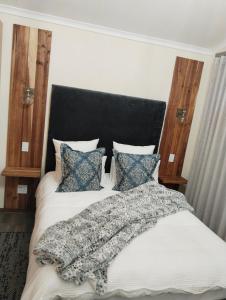 a bedroom with a bed with a black headboard and pillows at Melkbos Corner in Witbank