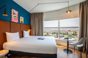 um quarto de hotel com uma cama, uma escrivaninha e uma janela em ibis Paris Porte de Montreuil em Paris mais 37 fotografias