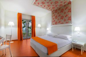 a bedroom with a bed and a table and a chair at Hotel Caparena in Taormina
