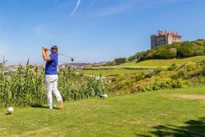 un uomo che gioca a golf su una collina con un castello sullo sfondo di Le Cocon du Hameau a Bidart