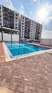 a swimming pool in front of a large building at Comfort meets convenience 3BR by Airport & SGR in Nairobi