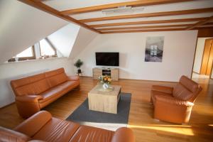 HopfmannsfeldFerienwohnung Heike的客厅配有皮革家具和电视