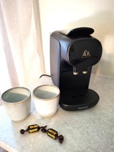 a coffee maker on a counter next to two measuring cups at Kattugglans Gästrum 1 in Ljungby