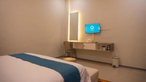 una camera da letto con un letto e una TV in una stanza di Grand Aulia Hotel Padang Panjang a Padangpanjang