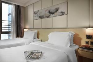 two beds in a hotel room with a magazine on top at Eco Tree Hotel Sheung Wan in Hong Kong +31 photos