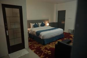 una camera da letto con un letto grande con cuscini blu di Grand Aulia Hotel Padang Panjang a Padangpanjang Altre 5 foto