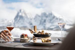 a table with a plate of food and glasses of wine at ADLER Alpe in Alpe di Siusi +39 photos