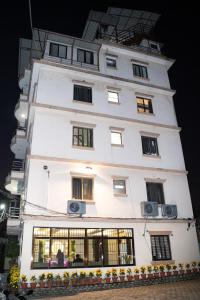 a tall white building with windows at Aarya Wellness & Hostel in Kathmandu
