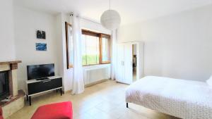 a white bedroom with a bed and a television at Maya Suite & Garden in Sarteano