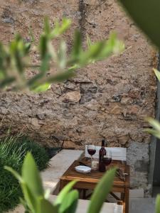 Una mesa con dos copas de vino y una pared de piedra en Concha Aurea Apartments, en Sveti Juraj